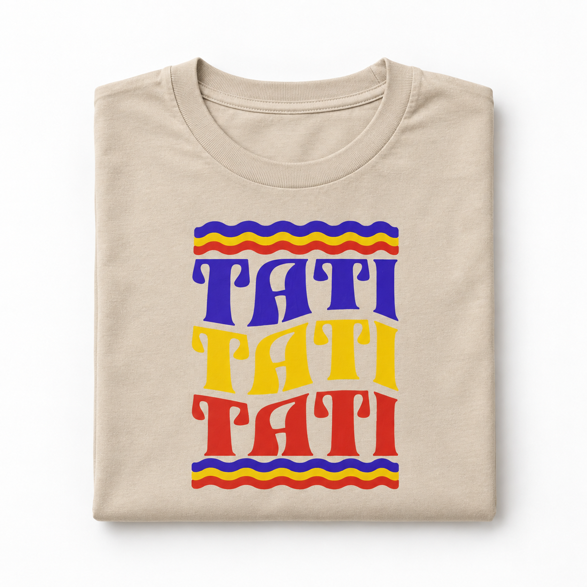 Groovy Rainbow Tati graphic on a folded sand T-shirt